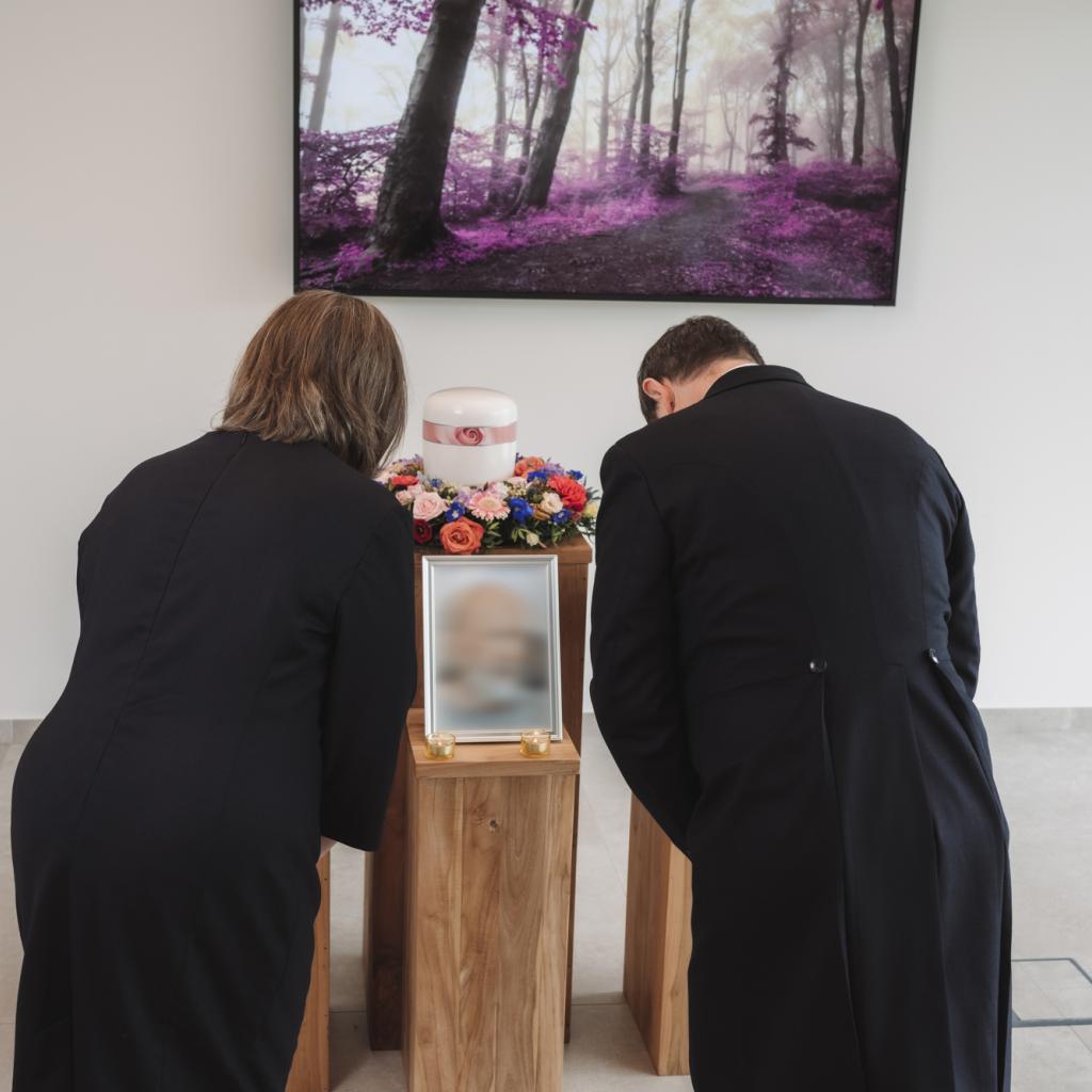 Annick en Gregory groeten de urne tijdens een afscheidsdienst in de aula